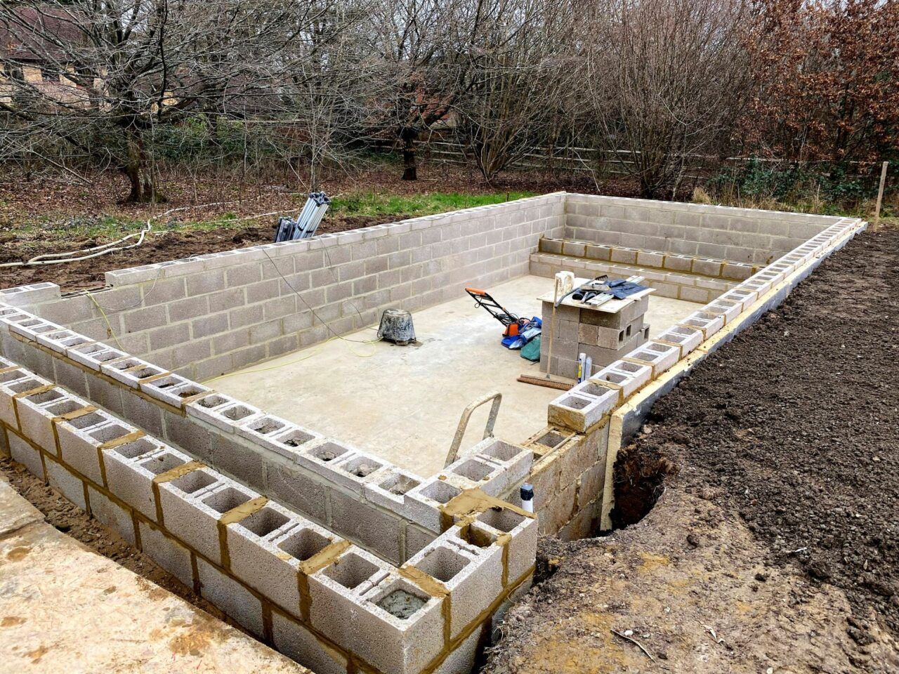 concrete block have been installed around the edge of the swimming pool