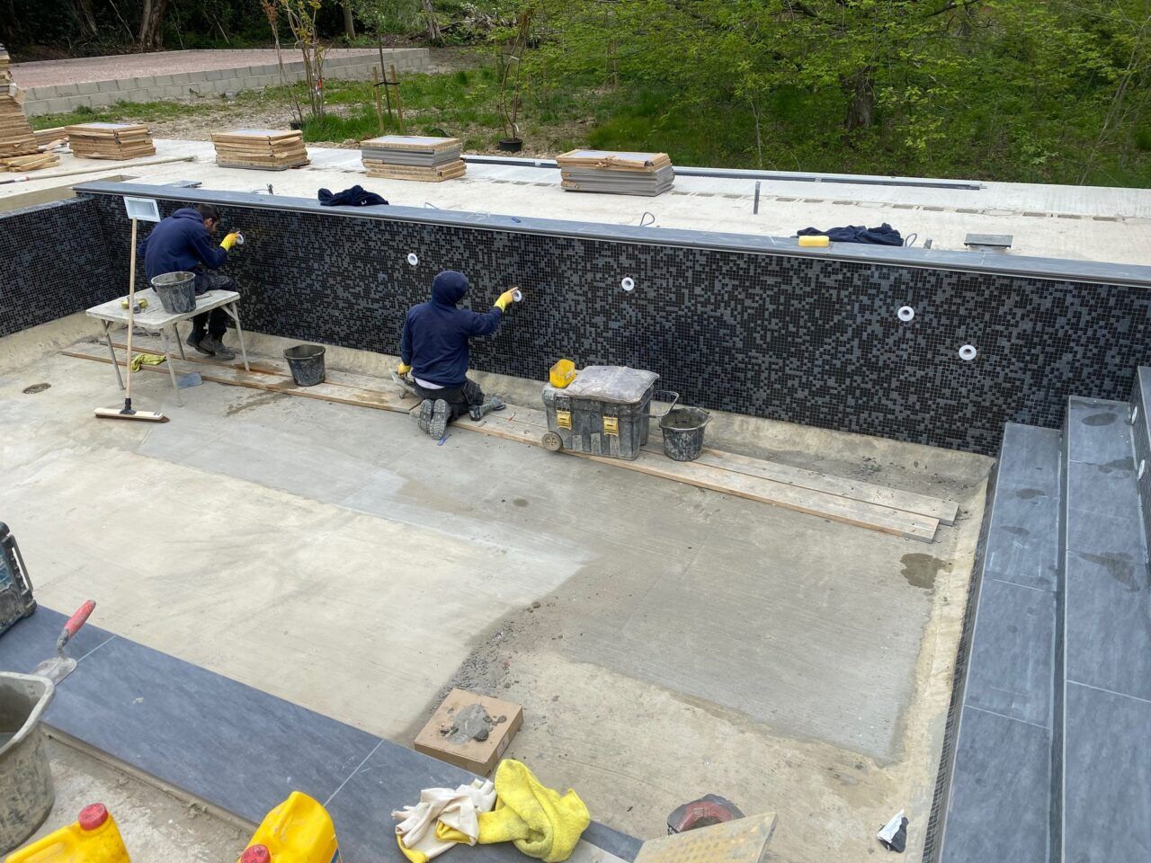 The team of UK Swimming Pools is finishing tiling around the water drain holes