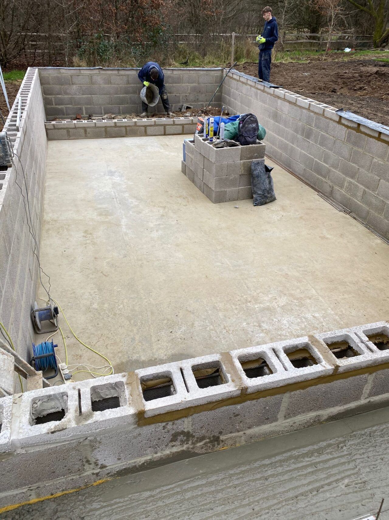 Removal of remaining debris from the pools edges and fresh concrete poured around the concrete blocks to increase stability