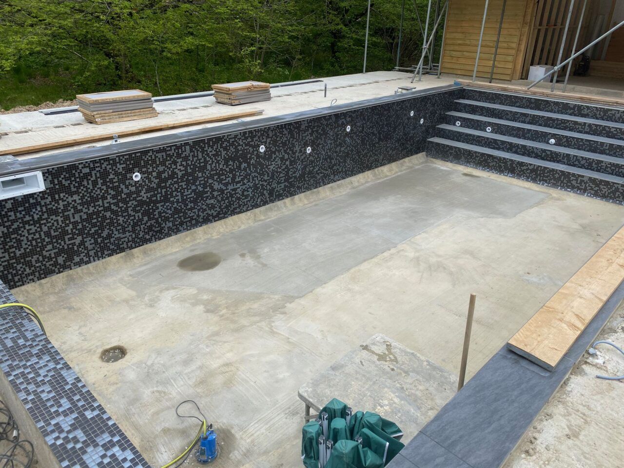 The bottom of the swimming pool is cleaned and ready for the new black and silver mosaic tiles