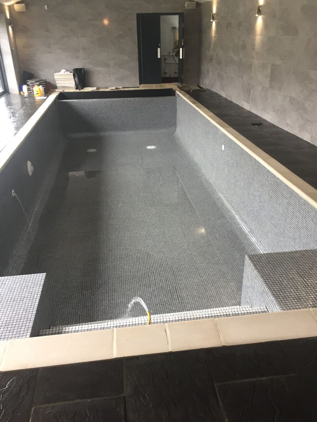 The cover was finished in a sleek grey, further enhancing the overall aesthetic appeal of the iridescent grey mosaic tiled swimming pool