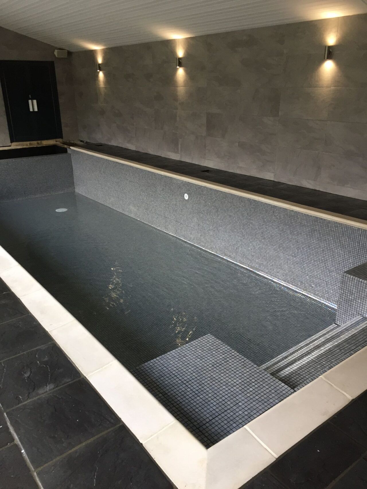 The cover was finished in a sleek grey, further enhancing the overall aesthetic appeal of the iridescent grey mosaic tiled swimming pool