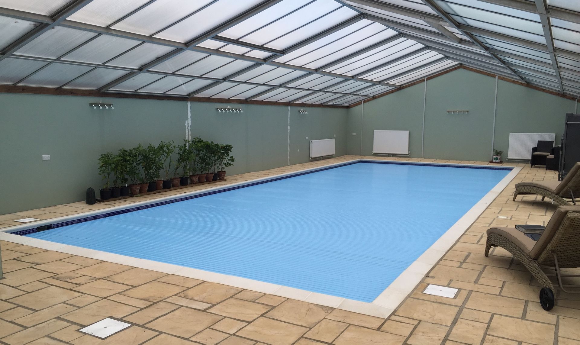 Newly installed semi-automatic retro-fit swimming pool cover on a refurbished kidney shaped swimming pool