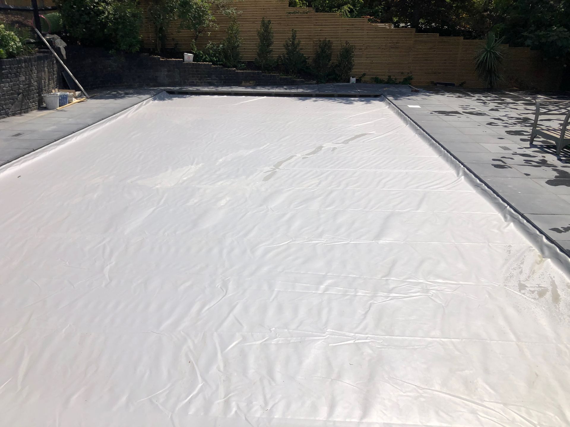Newly installed semi-automatic retro-fit swimming pool cover on a refurbished kidney shaped swimming pool