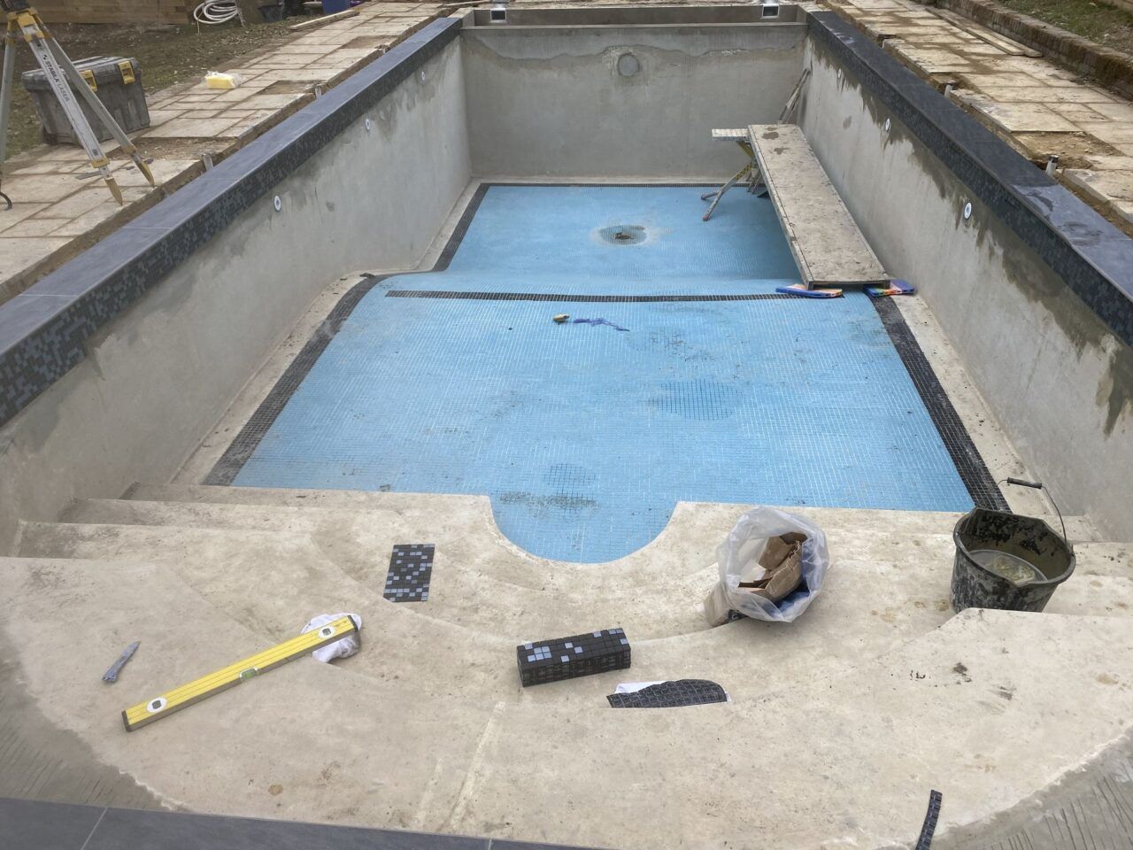 Installing a new mosaic tiled band to the refurbished swimming pool Installing a new mosaic tiled band to the refurbished swimming pool