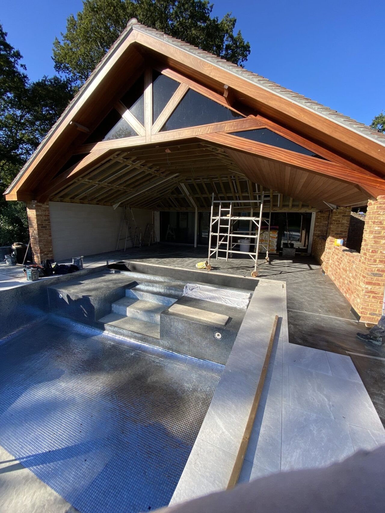The bottom of the swimming pool is getting tiled – starting from the side of the entrance to the pool The bottom of the swimming pool is getting tiled - starting from the side of the entrance to the pool