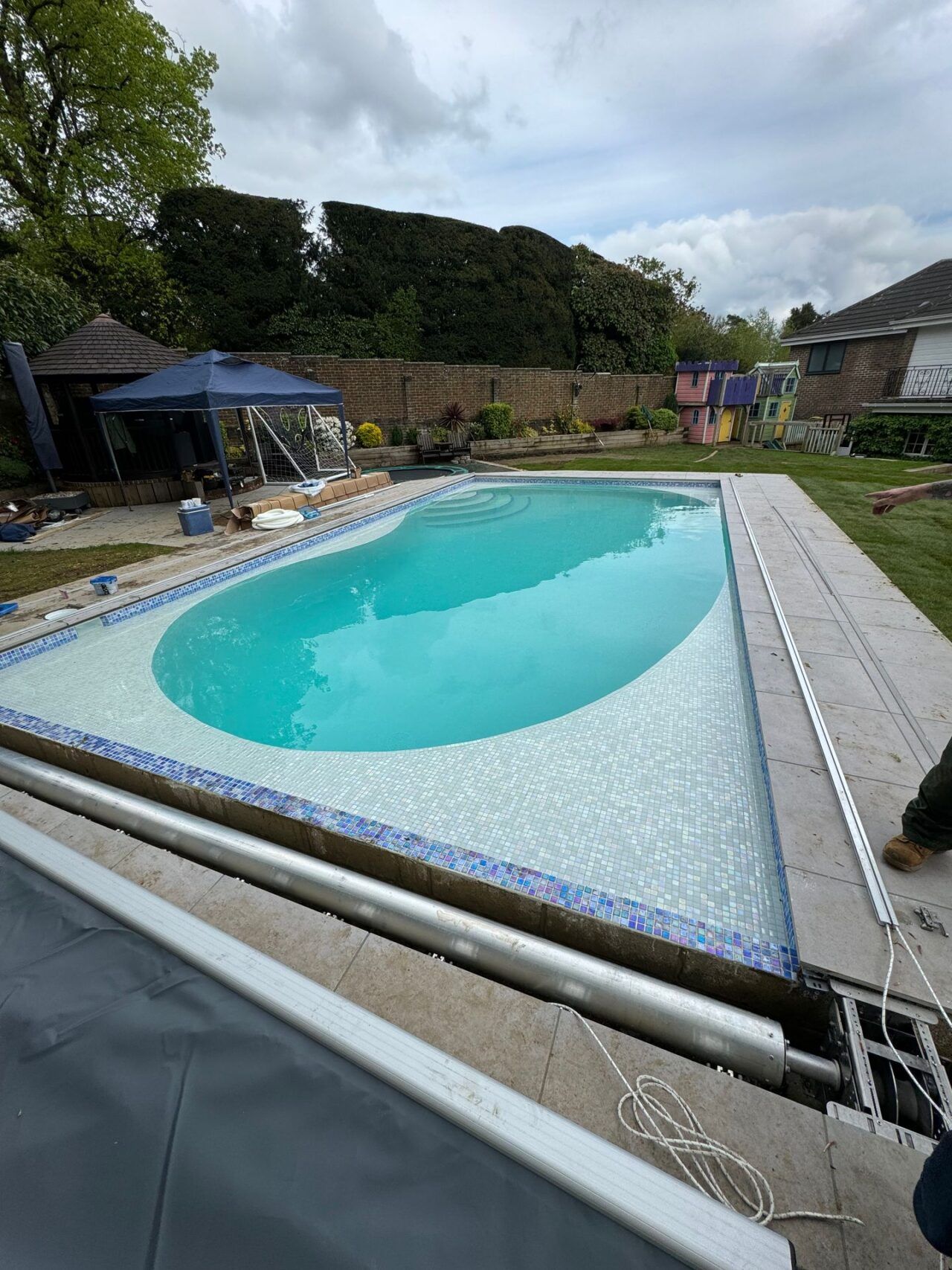 Pavings are being installed around the pool and over the automatic swimming pool cover Pavings are being installed around the pool and over the automatic swimming pool cover