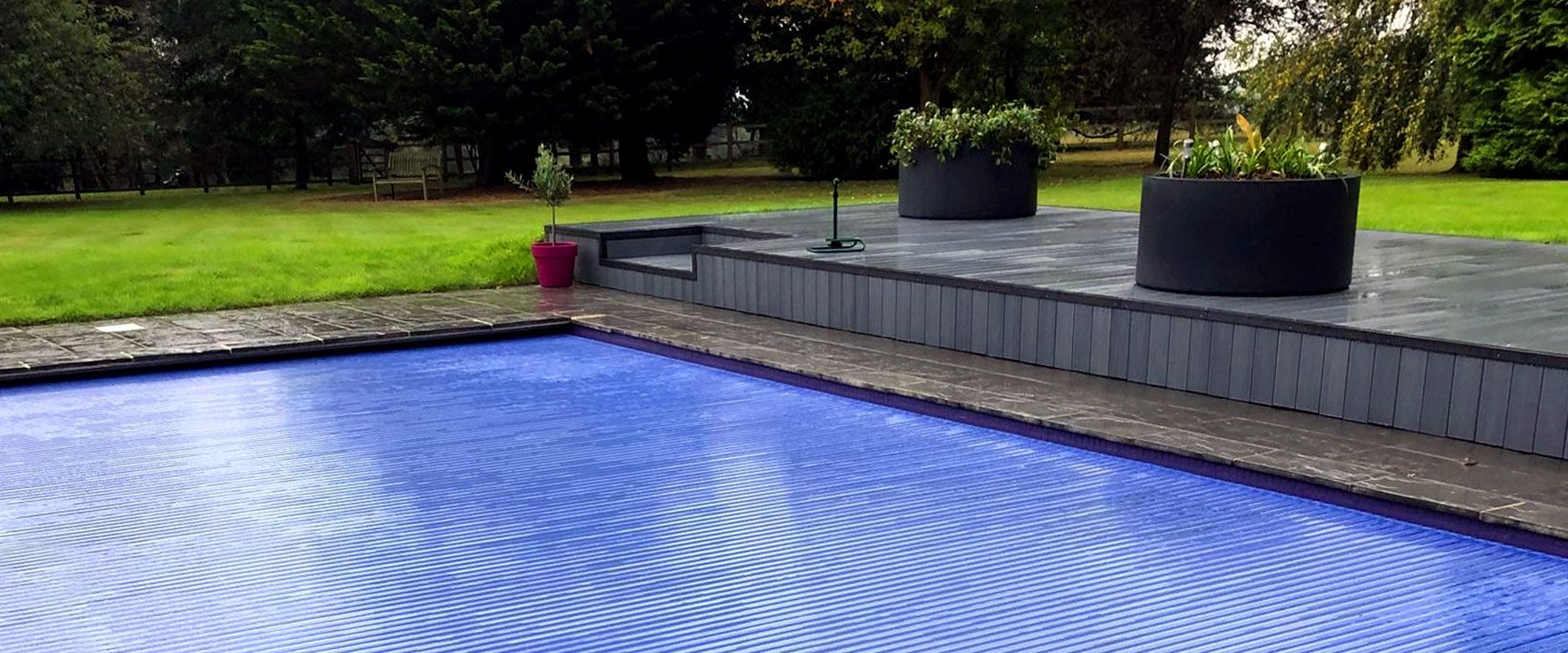 Newly installed semi-automatic retro-fit swimming pool cover on a refurbished kidney shaped swimming pool